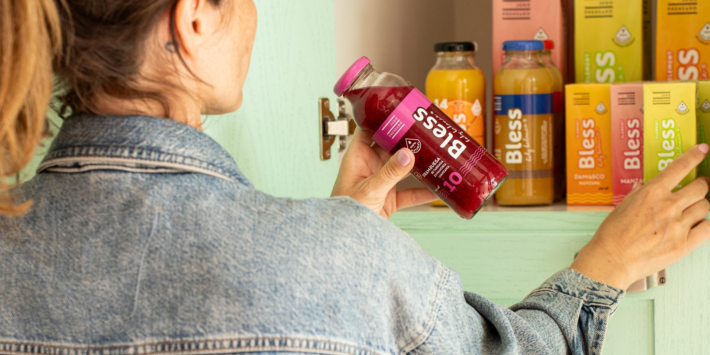 Mujer guardando jugos Bless en el mueble de la cocina